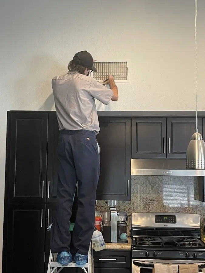 Technician inspecting an air vent during HVAC service in Pike Road